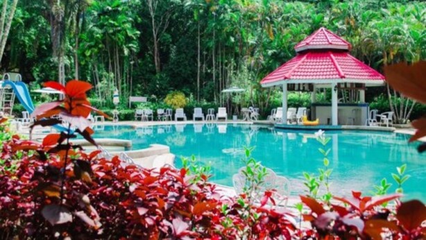 A pool area with lounge chairs and a gazebo.