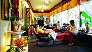 A traditional spa room with a massage chair, a statue, and a decorative altar.