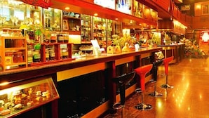 A bar area with a 'Fresh Coffee' sign, shelves with various items, and red bar stools.