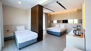 Habitación de hotel con dos camas, un escritorio pequeño con un hervidor y un televisor.