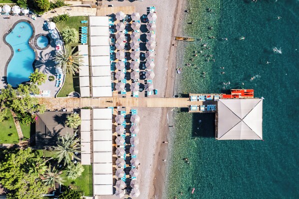An aerial view of a resort with a pool, beach area, and umbrellas.