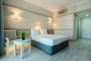 A hotel room with a bed, bedside tables, a small table with a plant, and wall-mounted lights. - Grand Ring Hotel (Kemer)
