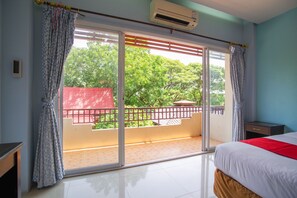 A hotel room with a large sliding glass door leading to a balcony, a bed with a red blanket, and an air conditioning unit on the wall. - OYO 384 Ban Sabaidee (Ayutthaya)