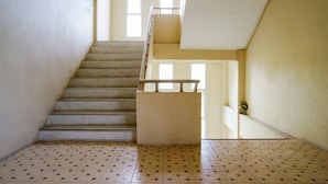 A staircase with a handrail, leading to an upper floor. The walls are plain and the floor has a patterned tile design. - OYO 384 Ban Sabaidee (Ayutthaya)