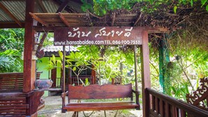 A wooden bench under a pergola with a sign in a foreign language. - OYO 384 Ban Sabaidee (Ayutthaya)