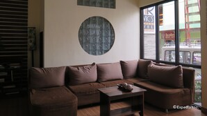 Ein modernes Wohnzimmer mit einem braunen Ecksofa, einem kleinen Holztisch und einem dekorativen, runden Wandbild.