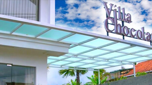 A modern building with a sign reading "Villa Chocolate" and a glass-covered entrance.