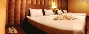 A hotel room with two beds, a wooden headboard, a bedside table with a lamp, and a bouquet of flowers. - Villa Chocolate (Parongpong)