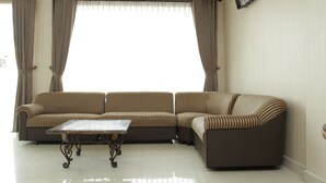 A living room with a sectional sofa, a coffee table, and curtains.