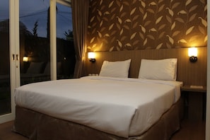 Une chambre d’hôtel avec un grand lit, deux tables de chevet et un mur décoré d’un motif.