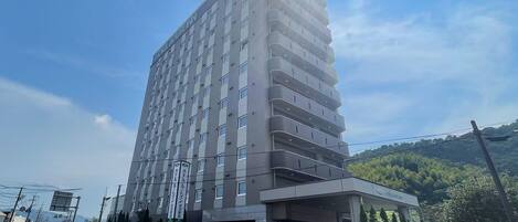 A multi-story hotel with a modern design, featuring a prominent entrance and a parking sign indicating EV charging availability.