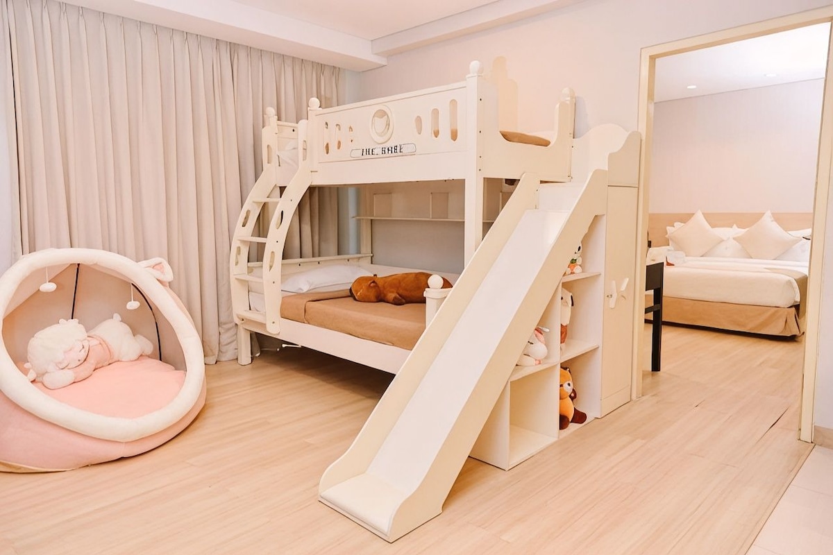 Una cama individual con tobogán, una silla colgante y una cama separada con almohadas.