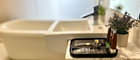 A bathroom with a white bathtub, a sink, and a countertop with a tray holding toiletries.