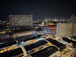 A modern hotel with multiple floors, a parking area, and a view of the cityscape at night.