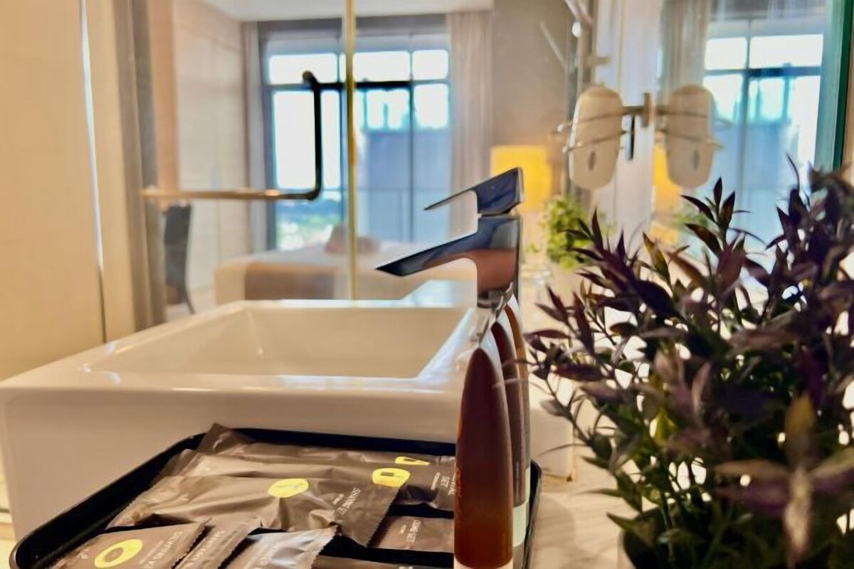 Un baño con lavamanos blanco, toallero y planta en maceta.