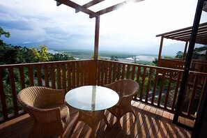 A wooden deck with wicker chairs and a glass table, overlooking a scenic landscape. - Yi-He Golden Homestay (Shoufeng)