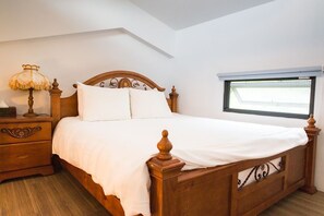 A wooden bed with white bedding in a room with a sloped ceiling and a window with blinds. - Yi-He Golden Homestay (Shoufeng)