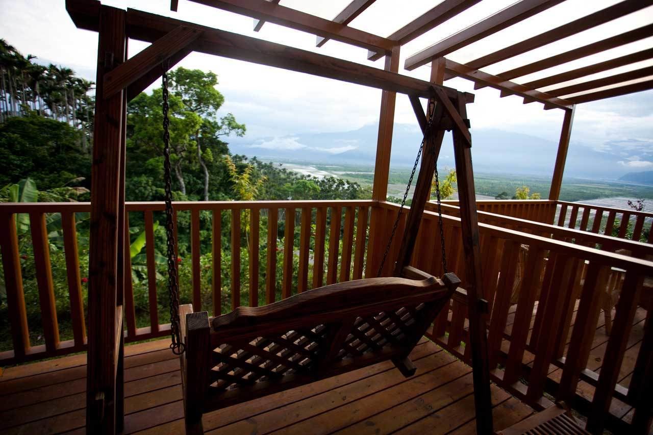 A wooden deck with a swing chair overlooking a lush landscape.