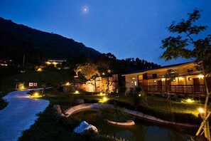 A hotel with a pool, outdoor lighting, and a mountainous backdrop. - Yi-He Golden Homestay (Shoufeng)