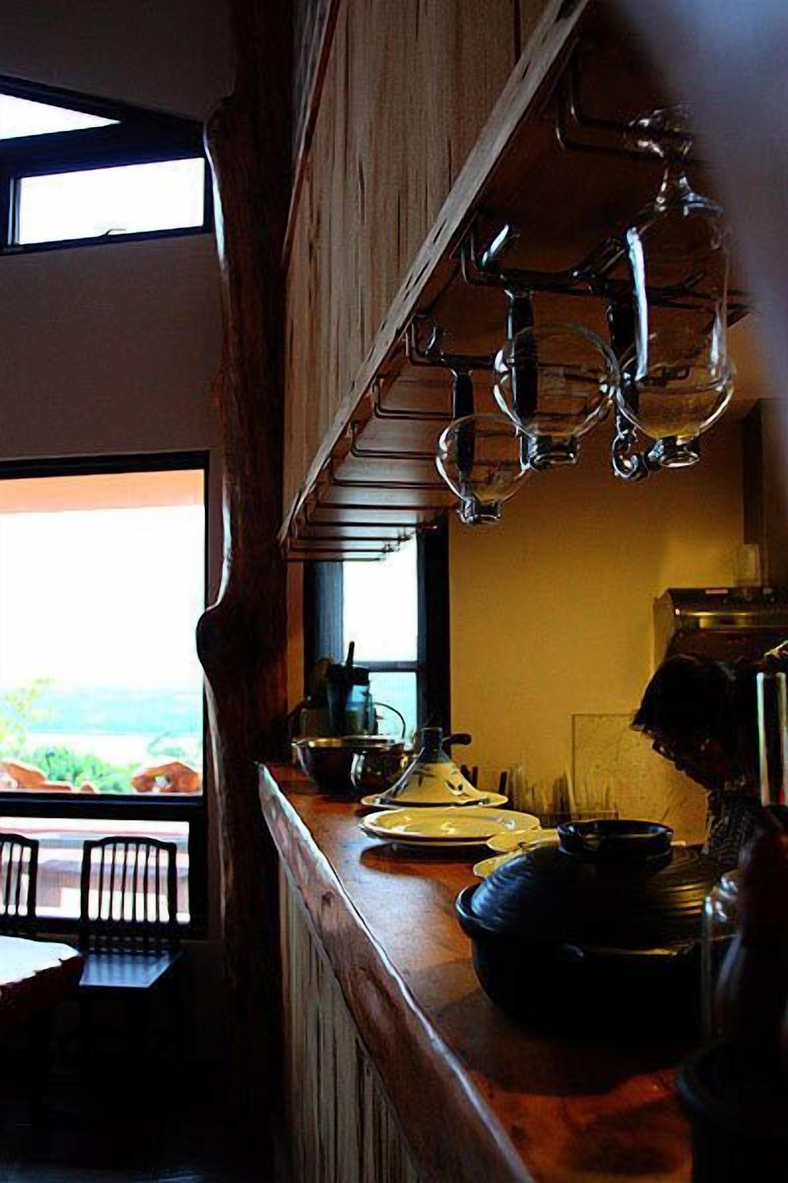 Una cocina con mostrador de madera, ollas colgantes y una ventana con vistas.