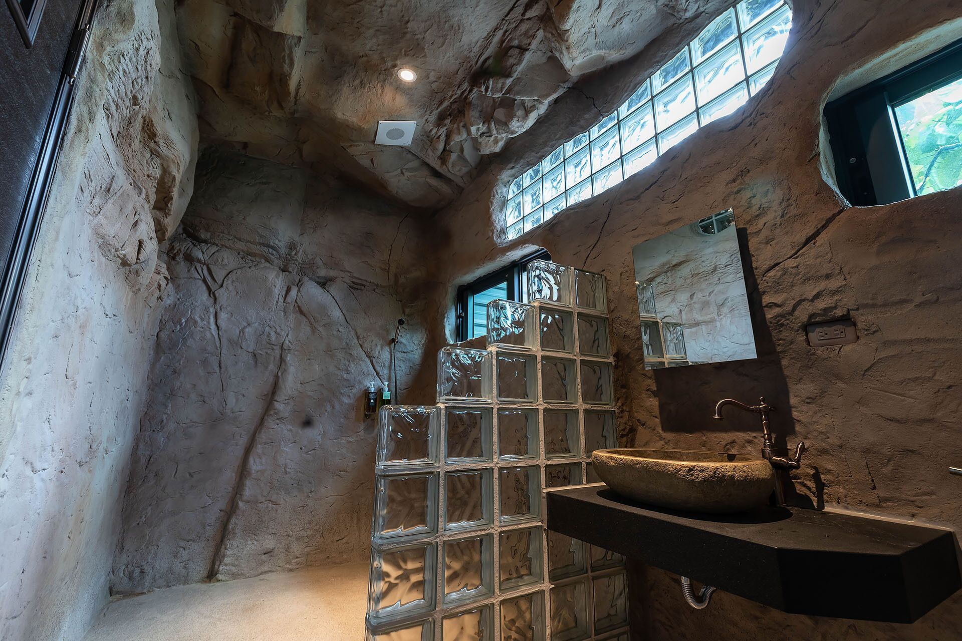 Un baño con lavamanos de piedra, un espejo y una ventana con vistas al exterior.