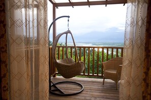 A wooden deck with wicker chairs and a hanging chair overlooking a scenic landscape. - Yi-He Golden Homestay (Shoufeng)