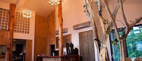 Un intérieur rustique avec des meubles en bois, une sculpture en forme d’arbre et des luminaires suspendus.