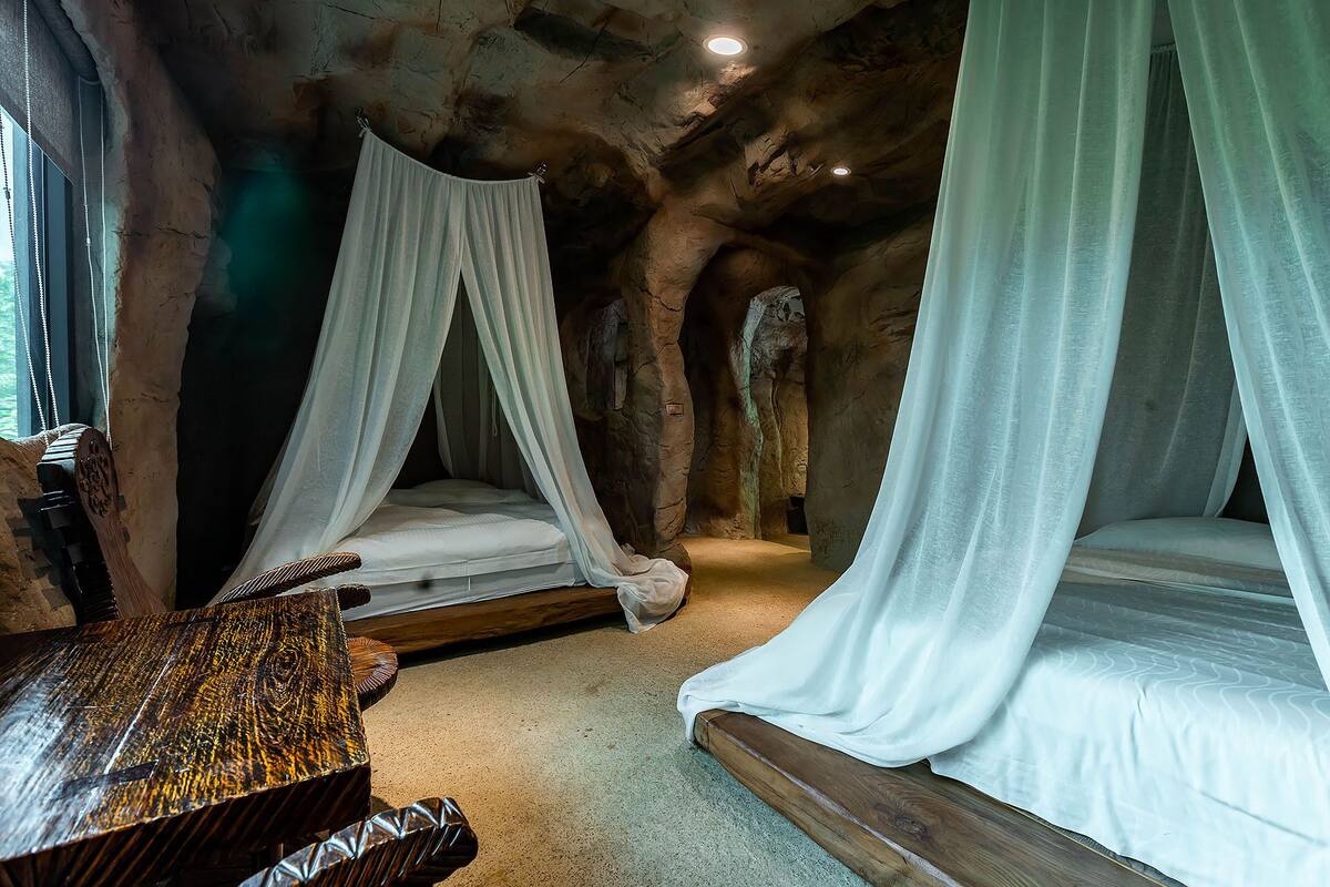 A rustic bedroom with two canopy beds, a wooden headboard, and a textured wall.