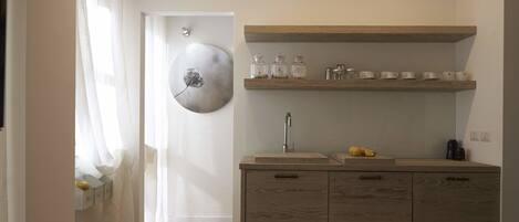 A compact kitchen with wooden cabinets, a sink, and a shelf with glass jars and cups.