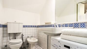 Ein Badezimmer mit Toilette, Bidet, Waschbecken und Waschmaschine.
