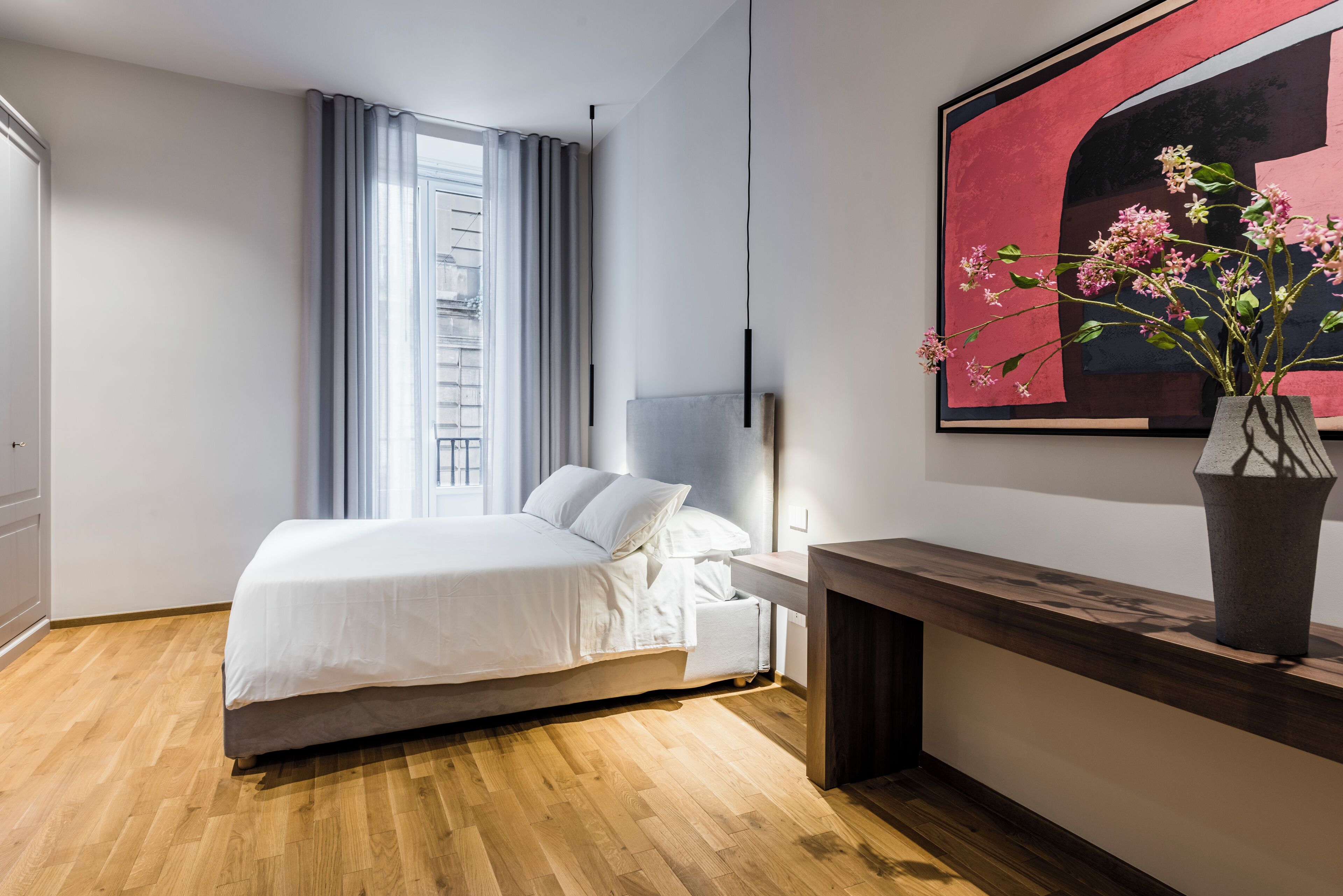Een moderne slaapkamer met een bed, nachtkastje en een groot abstract schilderij.