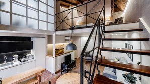 Un interior moderno con cocina, comedor y un altillo con escalera.