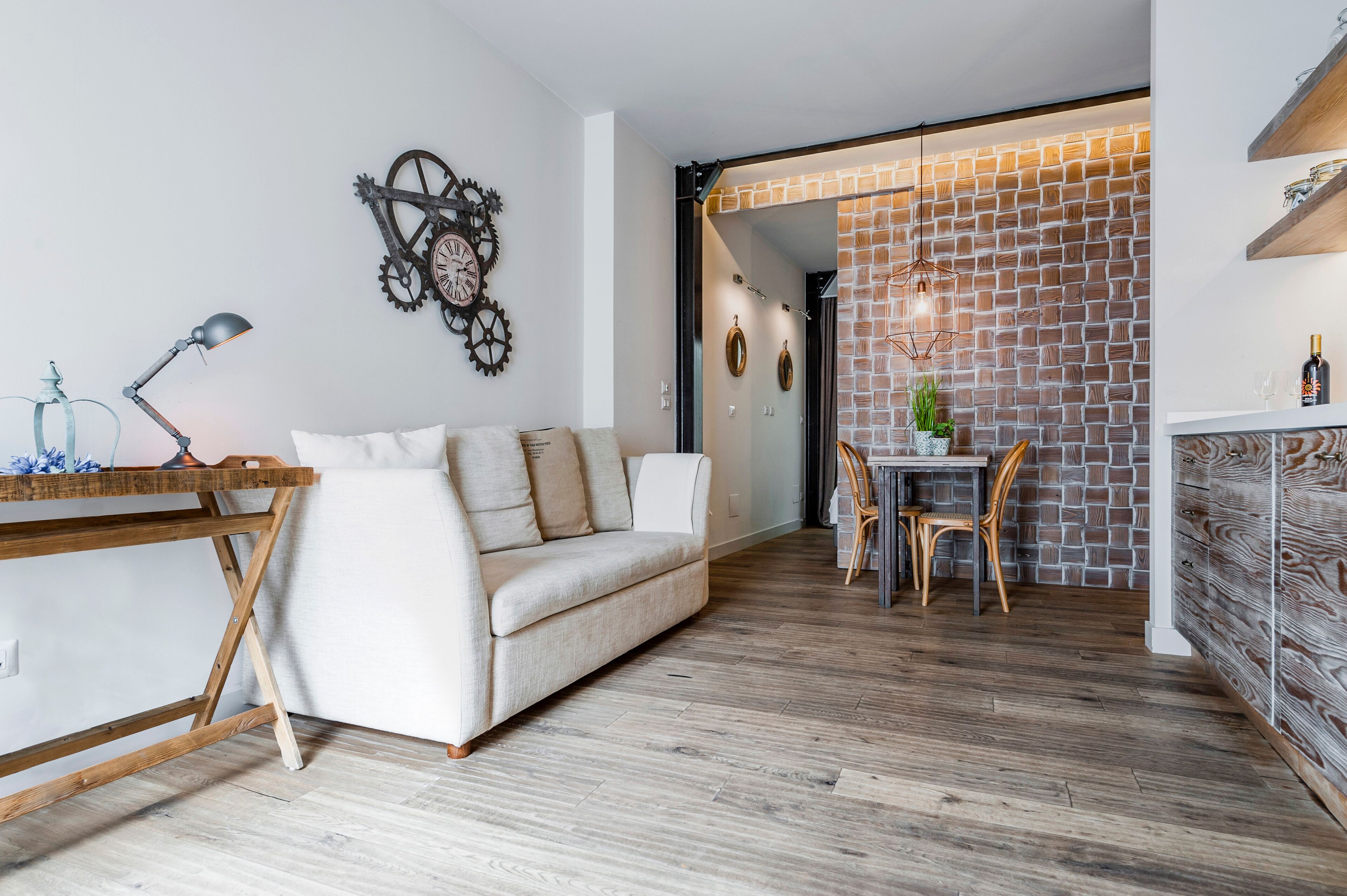 A modern living room with a sofa, a wooden table, and a dining area with chairs.