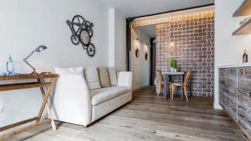 A modern living room with a sofa, a wooden table, and a dining area with chairs.