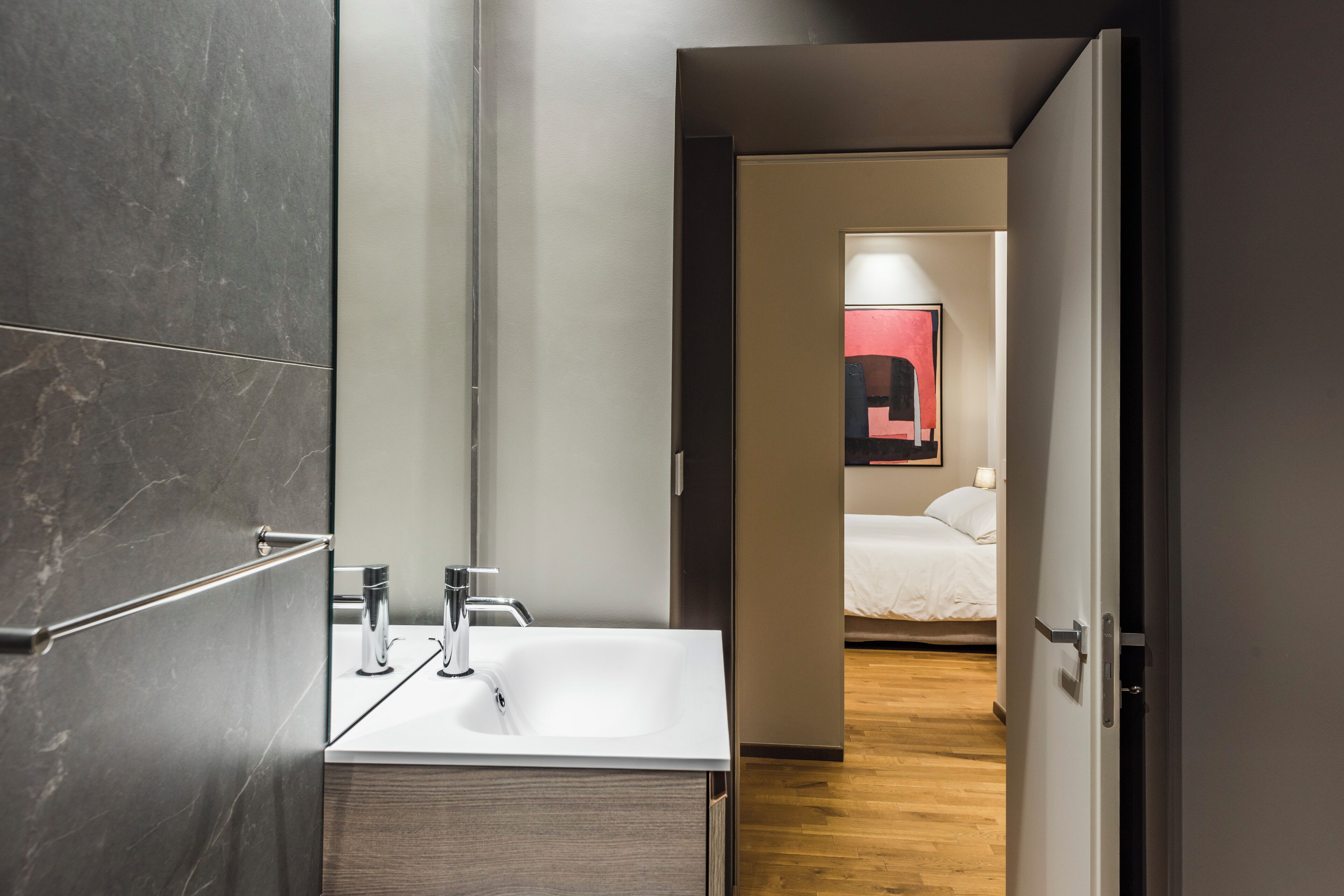 A modern bathroom with a large mirror, a sink, and a wooden cabinet.