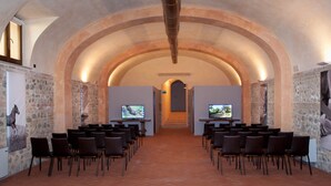 A conference room with a vaulted ceiling, stone walls, and two screens at the front. - Poggiovalle Tenuta Italiana (Fabro)