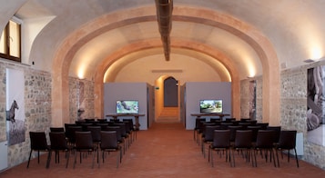 A conference room with a vaulted ceiling, stone walls, and two screens at the front.