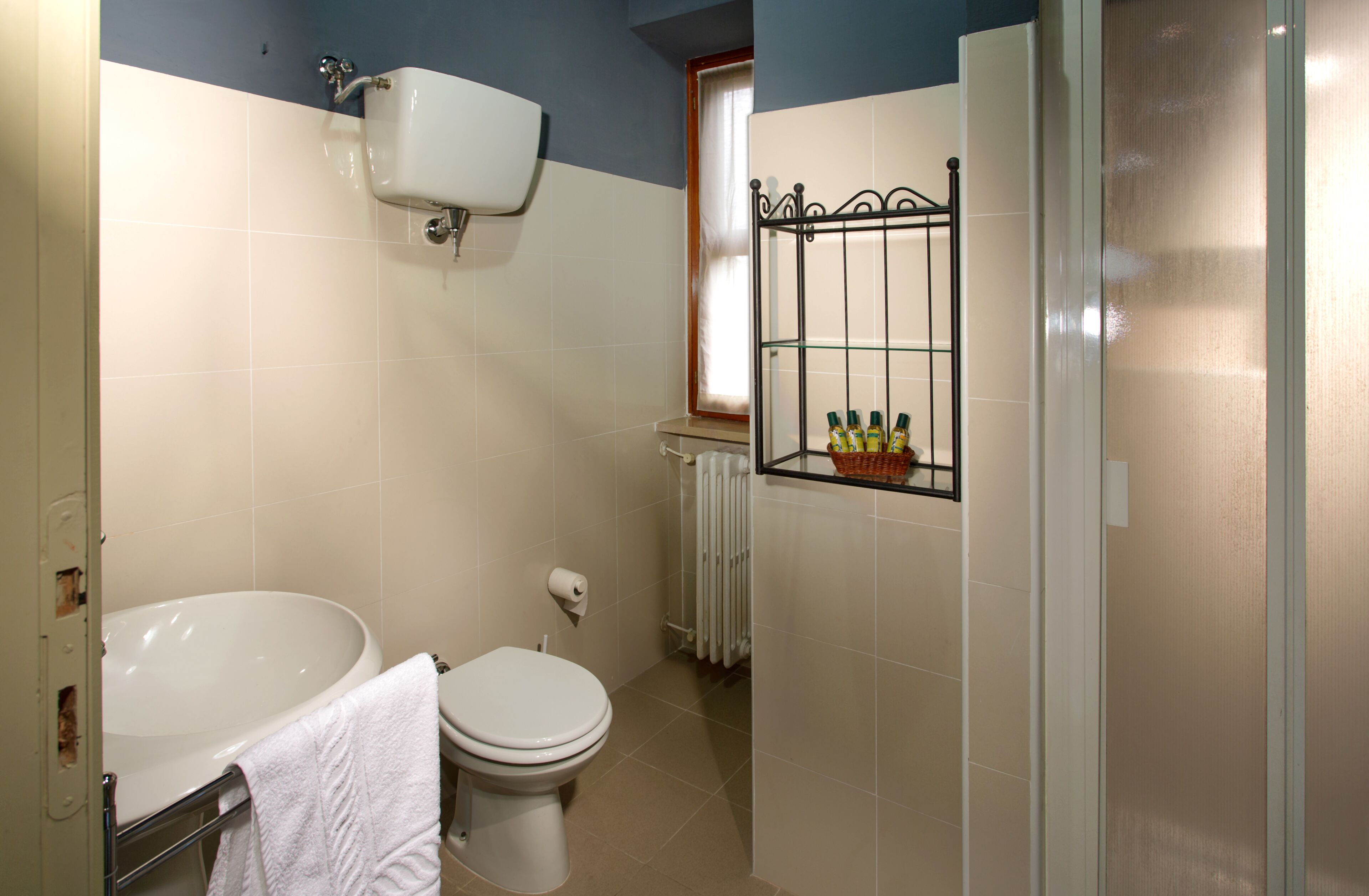 A bathroom with a bathtub, toilet, and a shelf with toiletries.