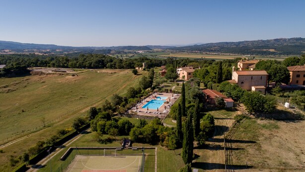 A large outdoor swimming pool surrounded by lush greenery and a tennis court. - Poggiovalle Tenuta Italiana (Fabro)