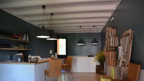 A bar area with wicker chairs, a counter with shelves of bottles, and a chalkboard menu. - Poggiovalle Tenuta Italiana (Fabro)