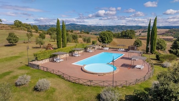 A pool area with a rectangular pool, sun loungers, and a wooden play structure.