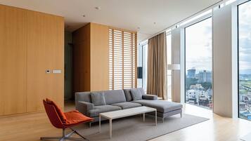 A modern living room with a sectional sofa, a red chair, a coffee table, and a large window offering a city view.