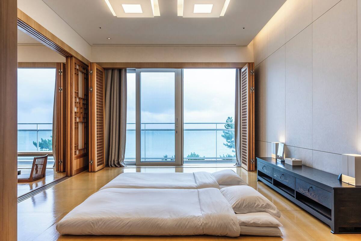 Quarto de hotel moderno com uma cama grande, um guarda-roupa de madeira e vista para o mar.