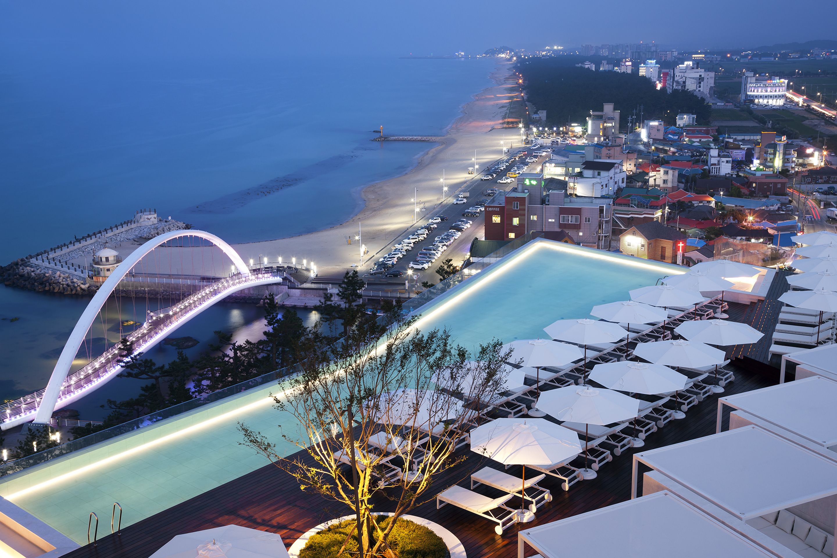 A resort with a swimming pool, lounge area, and a bridge over the water.