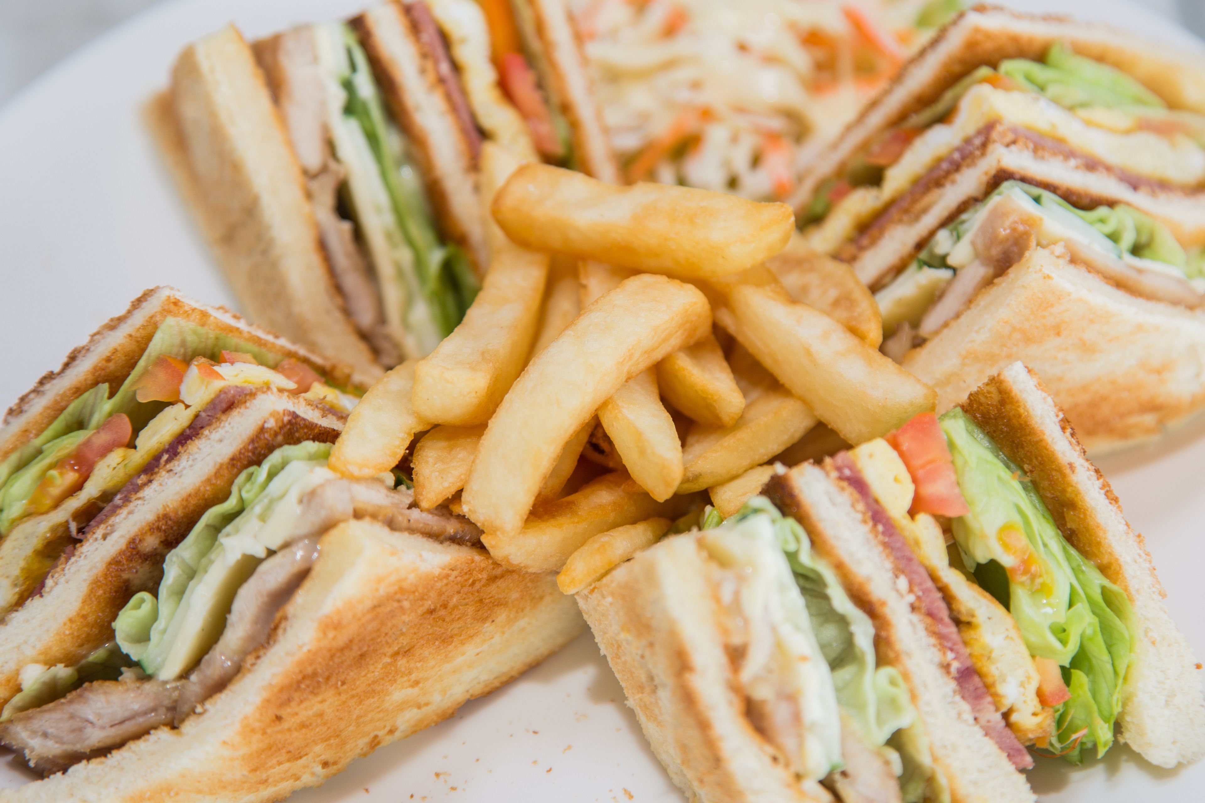 A plate with a sandwich cut into triangles and a pile of French fries.