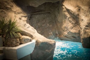 A cave-like interior with a water feature, rocky walls, and a plant in a planter. - Parkhotel Schmid (Adelsried)