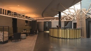 A modern lobby with a curved ceiling, a central bar area, and a seating arrangement with sofas and chairs. - Parkhotel Schmid (Adelsried)