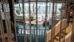 A spacious atrium with a central water feature, multiple levels with staircases, and various indoor plants. - Parkhotel Schmid (Adelsried)