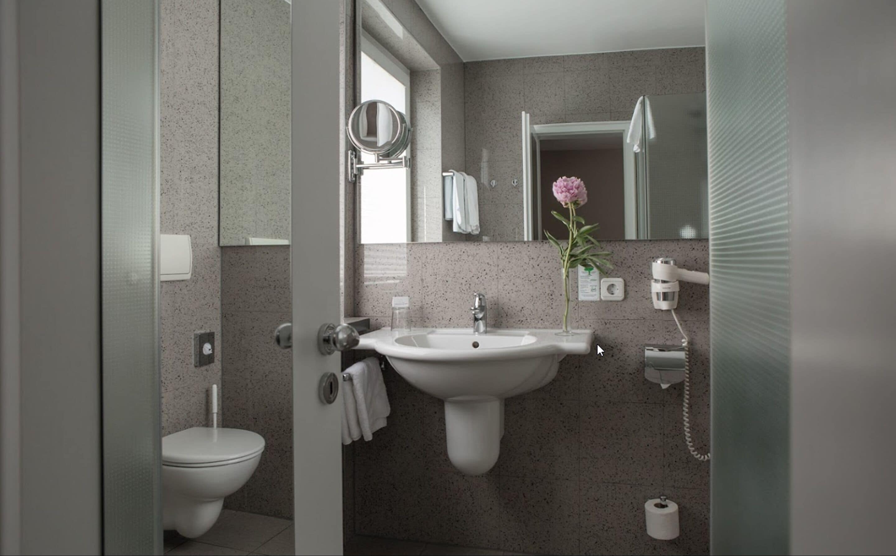 A modern bathroom with a sink, toilet, and a mirror.