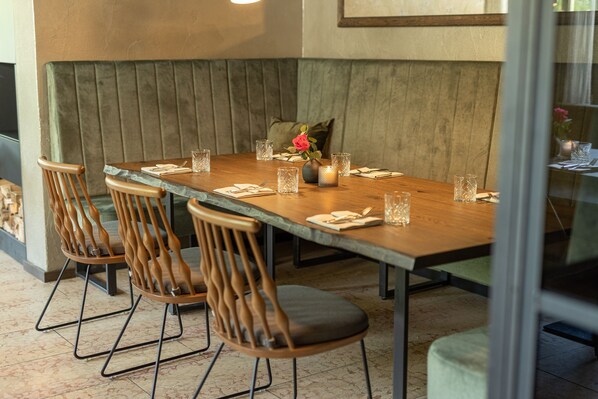 A dining area with a wooden table set for four, cushioned benches, and modern chairs.